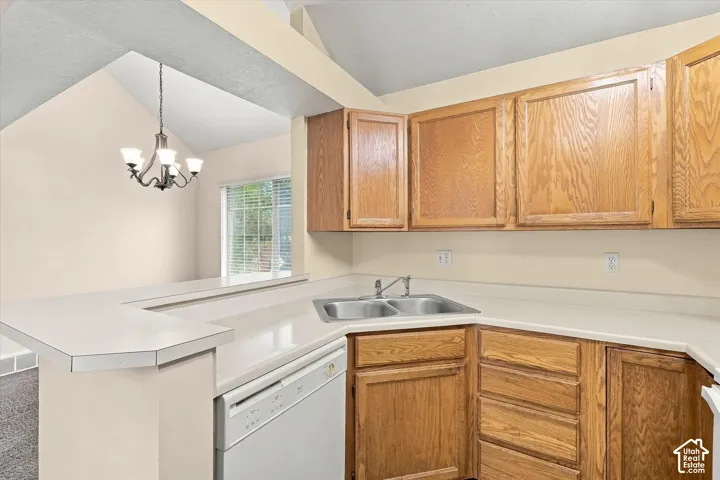 Kitchen featuring natural wood cabinetry, solid-surface countertops, dual-basin stainless steel sink, and vaulted ceilings