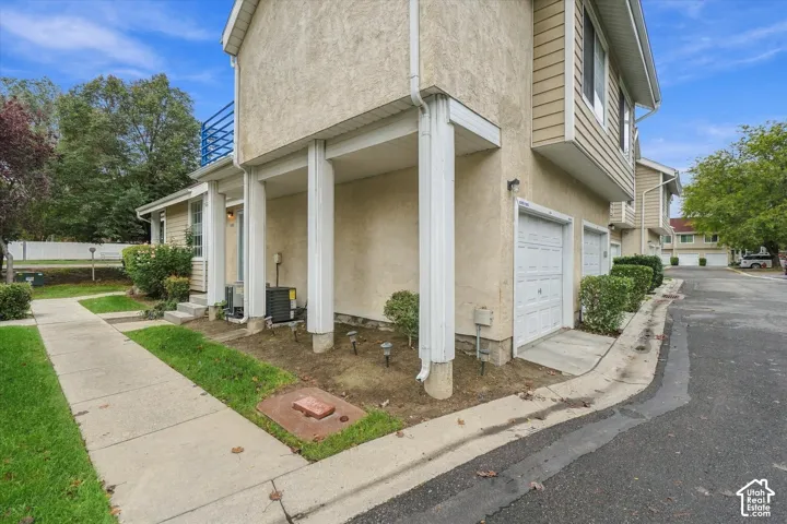 Multi-level exterior featuring stucco and horizontal siding, covered ground-level porch with structural columns, and one-car garage with paneled doors