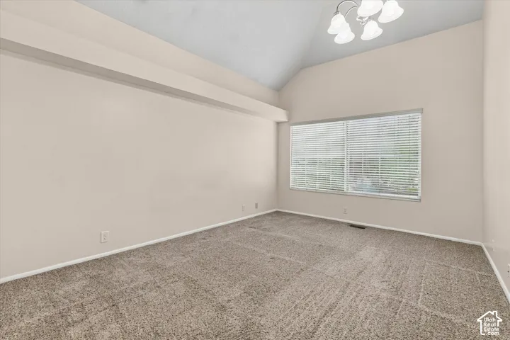 Primary Bedroom with vaulted ceilings featuring a multi-light chandelier and large window