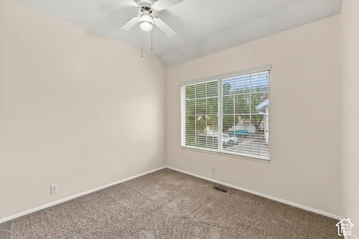 Bedroom #1 featuring vaulted ceilings, neutral-toned wall paint, neutral carpeting, and a ceiling fan with integrated lighting