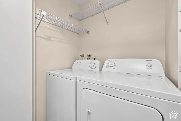 Laundry area featuring white appliances, wall-mounted metal shelving, and dedicated water hookups