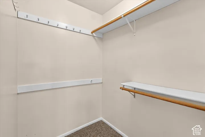 Primary Bedroom-walk-in closet featuring dual-level shelving with integrated hanging rods and a wall-mounted hook rack
