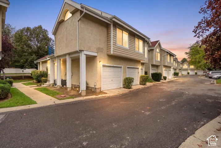 Multi-level exterior featuring stucco and horizontal siding, an attached one-car garage, and a gabled roofline with a decorative arched window