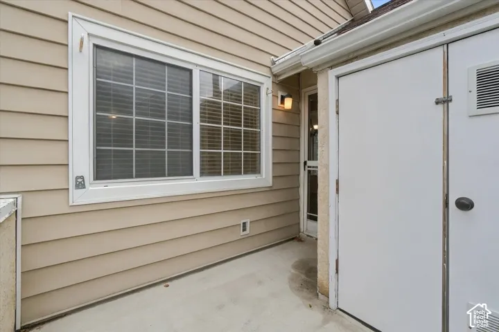 Private balcony siding with integrated wall-mounted light fixture, concrete patio, and built-in storage unit