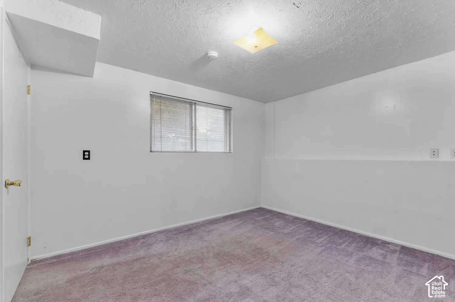 Interior room featuring wall-to-wall carpeting, a sliding window with horizontal blinds, and a centered flush-mount ceiling light fixture