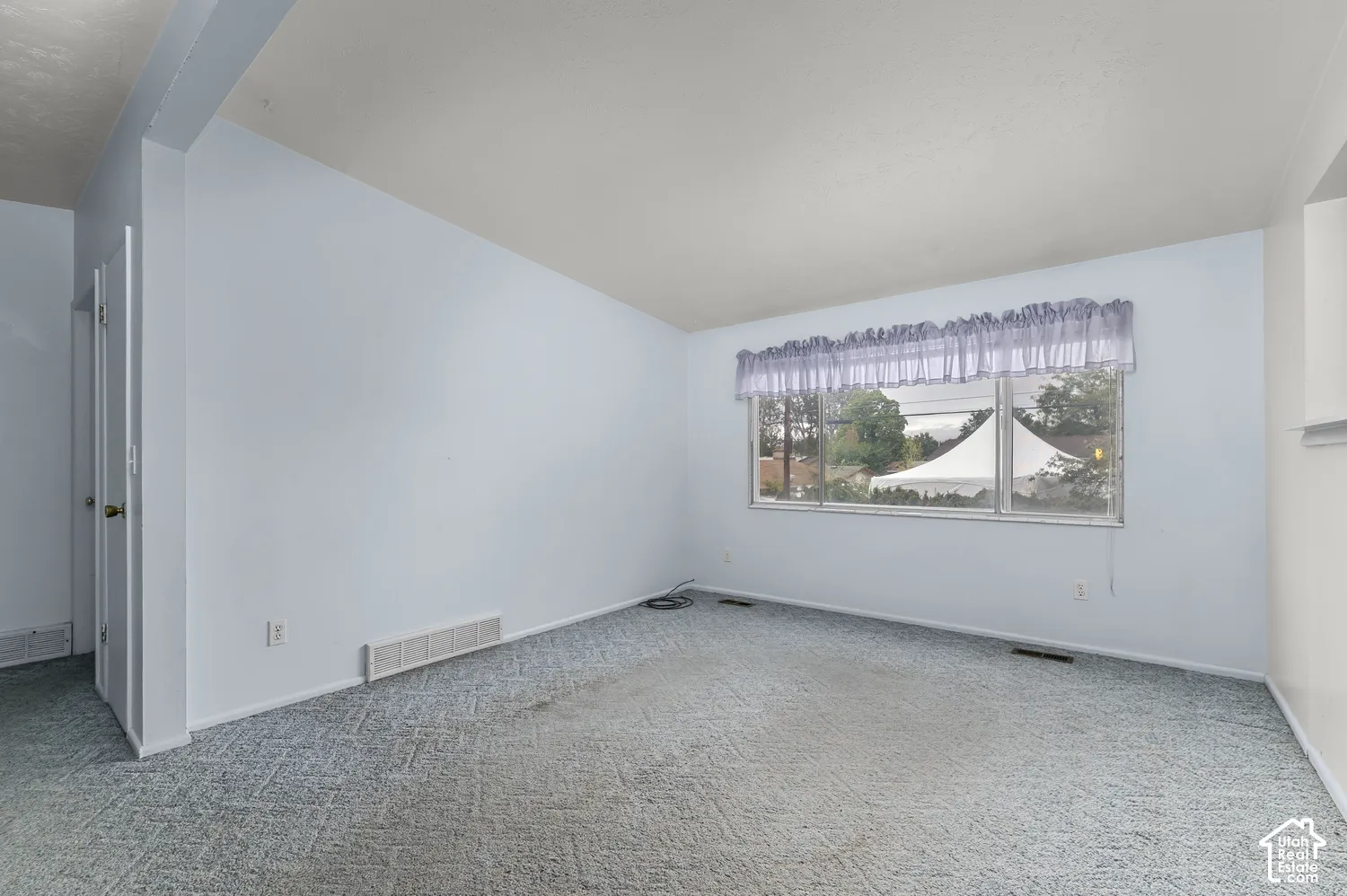 Interior room featuring neutral wall paint, carpeted flooring, and a large horizontal window