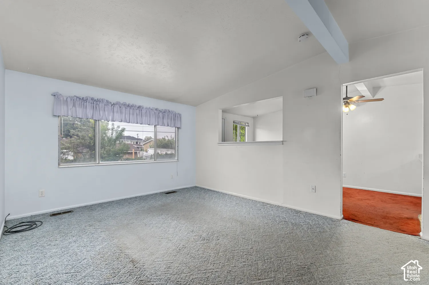 Interior space featuring an expansive window, a built-in wall pass-through, and a ceiling-mounted beam