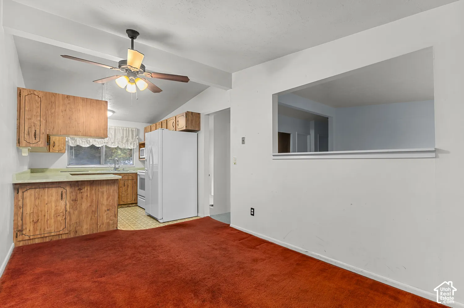 Kitchen featuring natural wood-finish cabinetry, solid-surface countertops, a stainless steel sink, and a ceiling-mounted fan with light fixture
