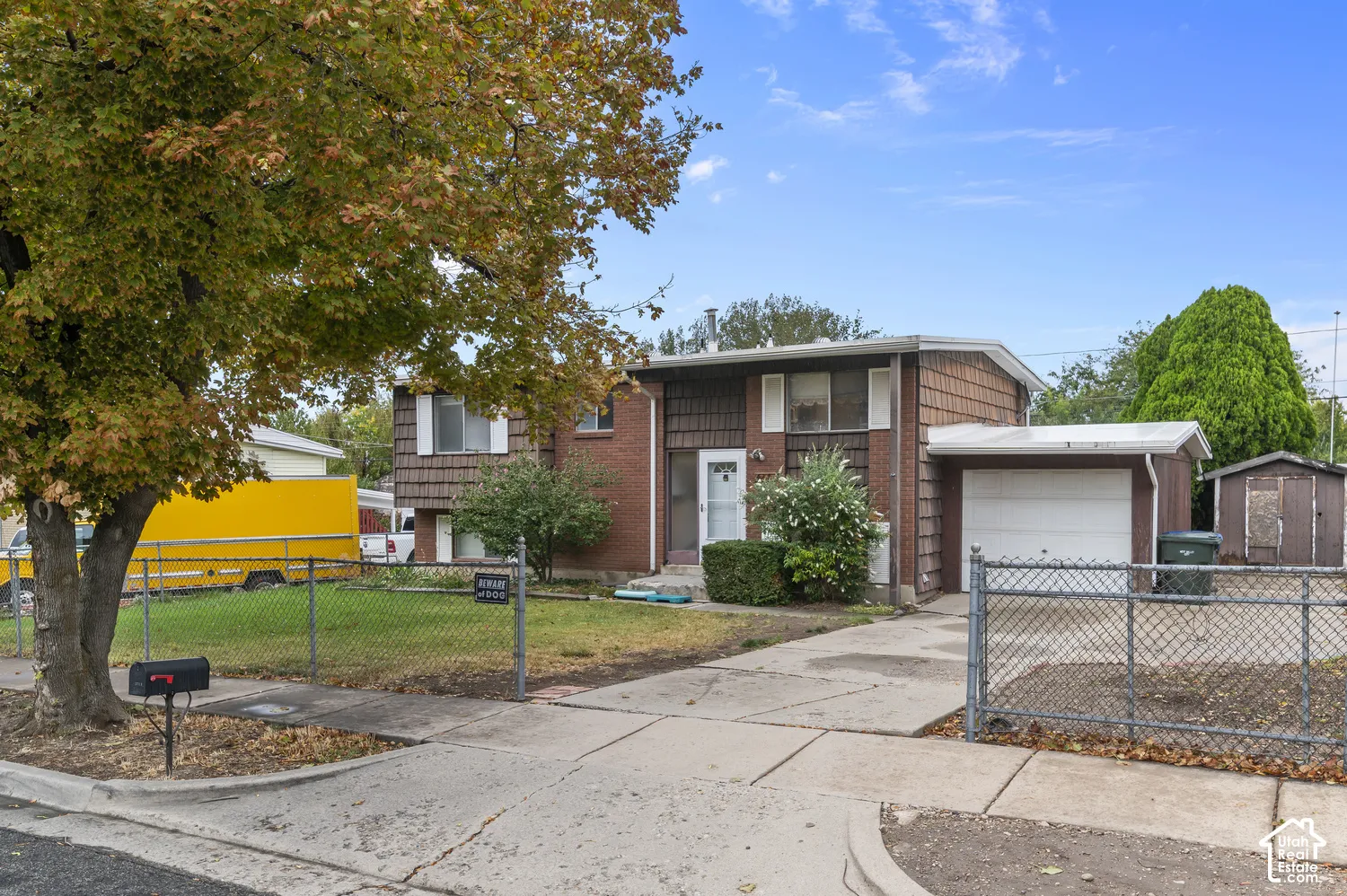 Split-level exterior featuring a brick and shake-style siding facade, single-car attached garage, and paved driveway
