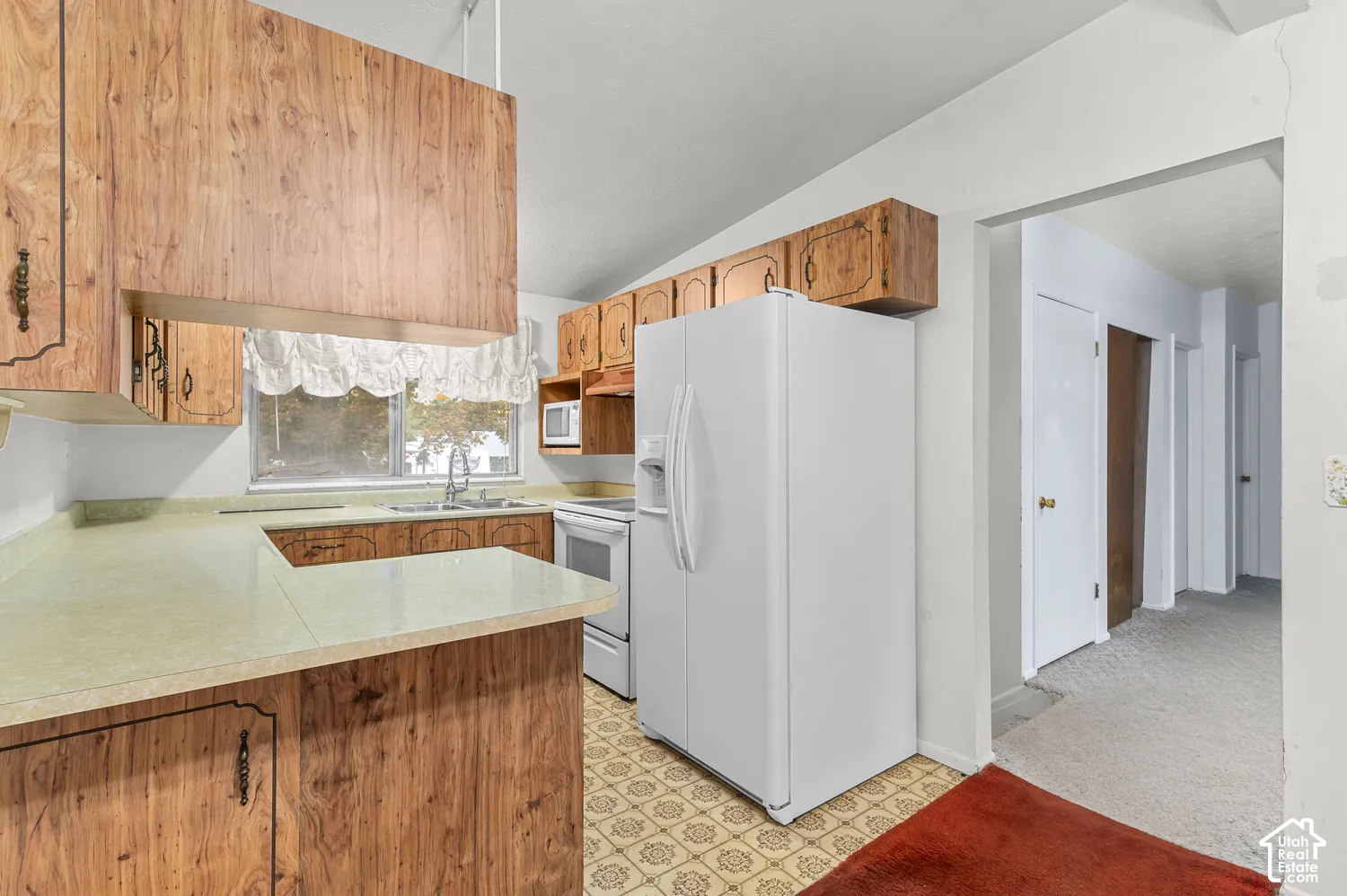 Kitchen featuring wood-finish cabinetry, solid-surface countertops, stainless steel sink, and patterned flooring