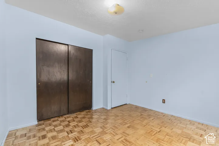 Room featuring wood-finish parquet flooring, dual sliding wood-grain closet doors, and a central ceiling-mounted light fixture