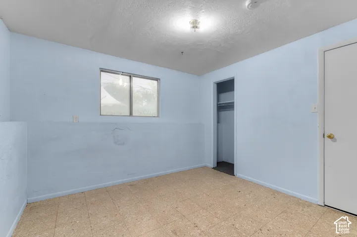 Interior room featuring textured flooring, a sliding window with horizontal blinds, and a built-in closet with a hanging rod