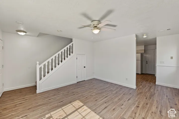 Interior area featuring wood-finish flooring, staircase with white railing, built-in under-stair storage, recessed lighting, and a ceiling fan