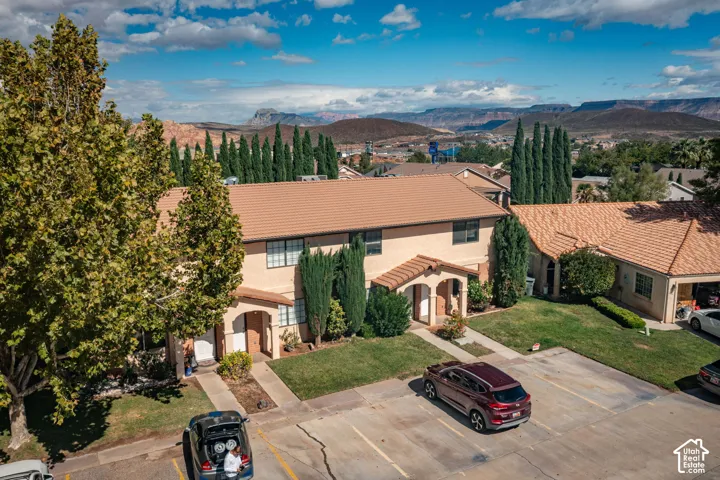 Two-story stucco exterior with a tile roof, arched entryway details, and mountain backdrop