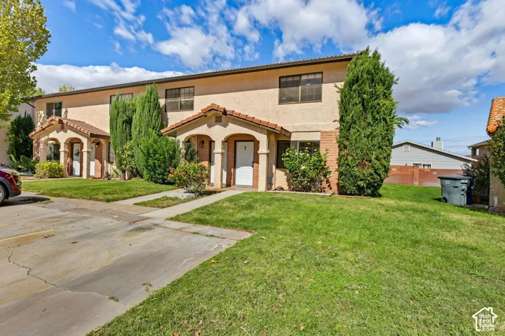 Two-story exterior featuring stucco siding, tile roof accents, arched covered entryways, and concrete walkways