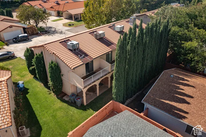 Multi-level exterior featuring a tile roof, stucco finish, balcony with metal railing, and lower-level arched supports