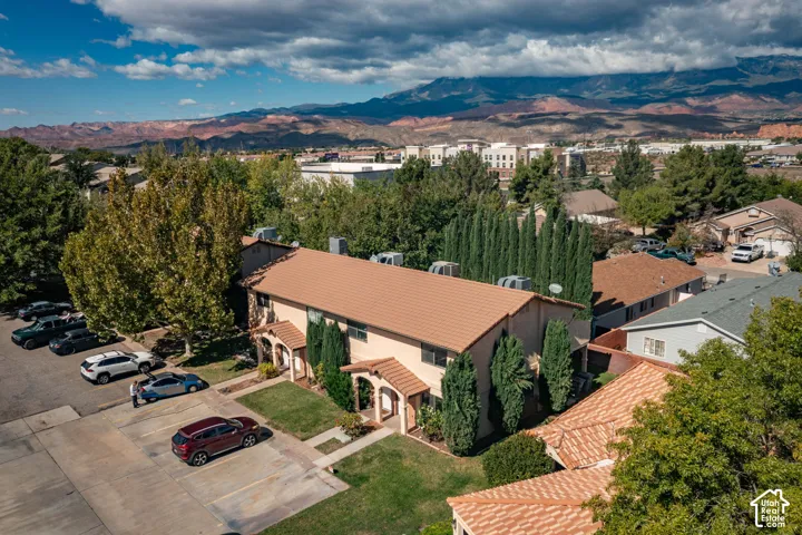 Two-story exterior featuring a pitched tile roof, stucco siding, and arched entryway with mountain backdrop