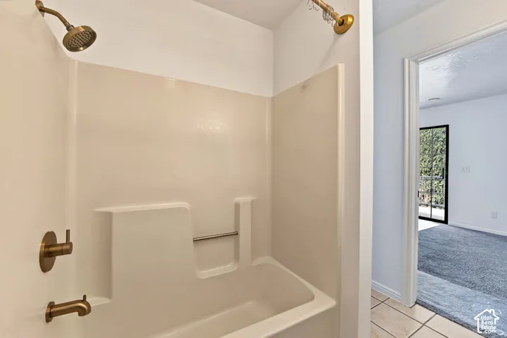 Shower and bathtub combination featuring a molded surround and brass-toned fixtures