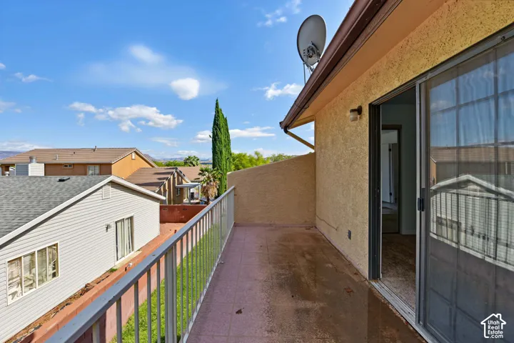 Elevated balcony featuring metal railing, tiled flooring, stucco siding, and sliding glass door access