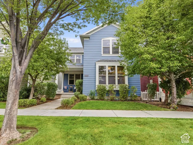Blue lap siding exterior featuring a covered front porch, a box bay window, white window trim, and mature landscaping