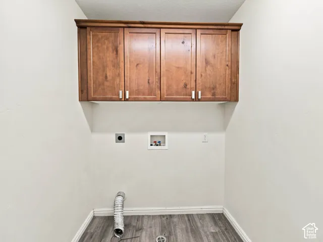 Wall-mounted wooden cabinetry with crown molding, wood-finish flooring, and recessed washer and dryer hookups