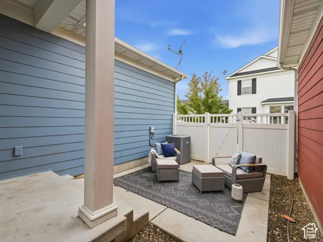 Private concrete patio featuring horizontal lap siding, a structural support column, and white vinyl privacy fencing
