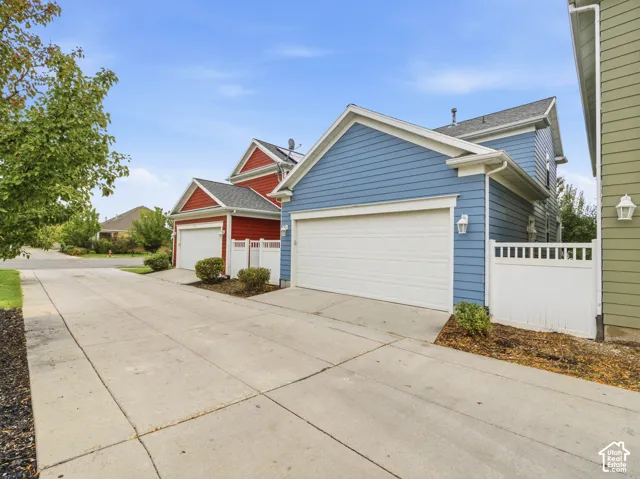Exterior featuring horizontal lap siding, multi-car garage, concrete driveway, and white vinyl privacy fencing