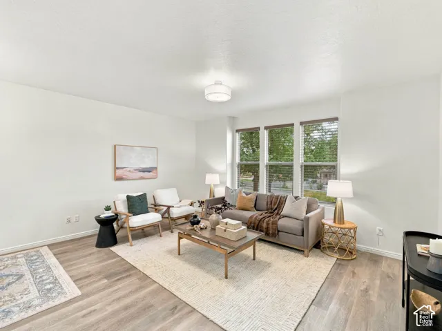 Living area featuring wood-finish flooring, a triple-pane window configuration, and a drum-style flush mount ceiling light