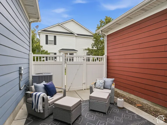 Private patio area featuring concrete hardscaping, horizontal lap siding, and a vinyl privacy gate