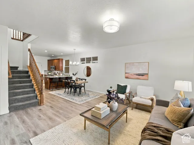 Open-concept living space featuring wood-finish flooring, a staircase with a wooden banister, recessed lighting, and a kitchen equipped with wooden cabinetry