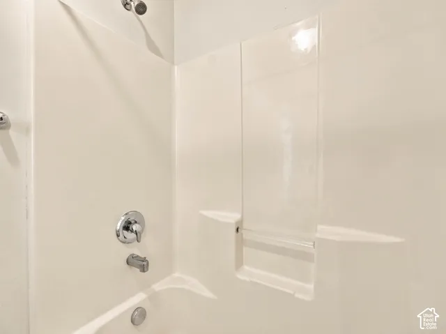 Bathtub and shower surround featuring a molded integrated shelf, chrome finish faucet, mixing valve, and wall-mounted shower head
