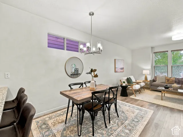 Open-concept interior featuring wood-finish flooring, a multi-light metal chandelier, horizontal transom window, and stone-surface breakfast bar