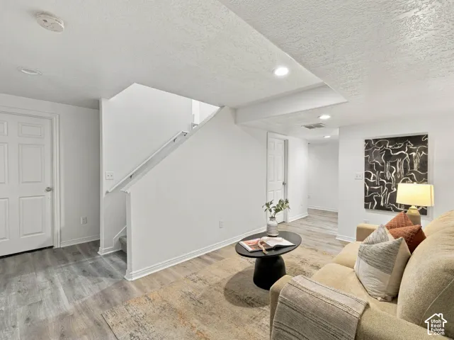 Interior space featuring wood-finish flooring, recessed lighting, and a painted staircase with a handrail