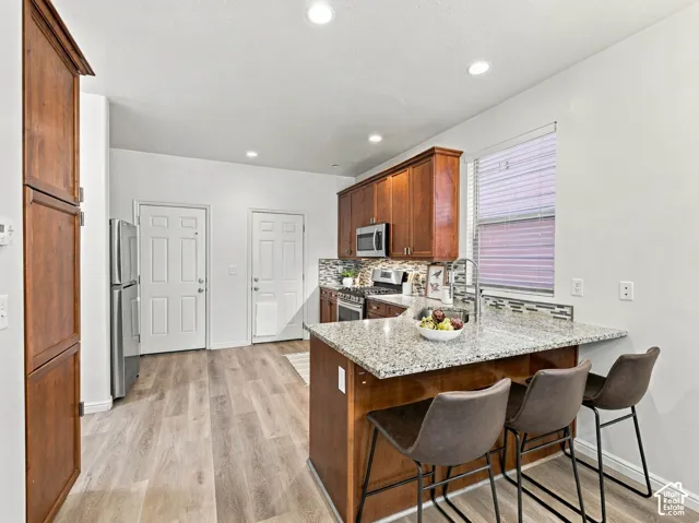 Kitchen featuring wood cabinetry, stone-surface countertops, tile backsplash, wood-finish flooring, and recessed lighting