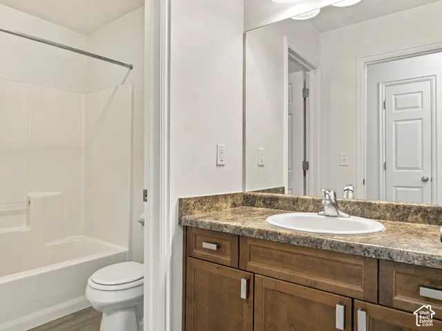 Bathroom vanity featuring wood-finish cabinetry, a patterned countertop, integrated oval sink, and a full-width wall mirror