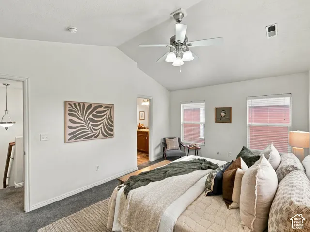 Vaulted ceiling with a central brushed nickel ceiling fan and light fixture, neutral carpeted flooring, and dual double-pane windows