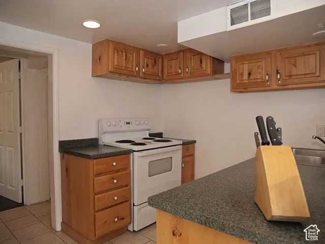 Kitchen featuring wood cabinetry, stone-finish countertops, recessed lighting, and tile flooring