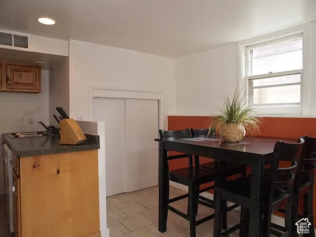Kitchen area featuring wood cabinetry, solid surface countertops, tile flooring, and sliding closet doors