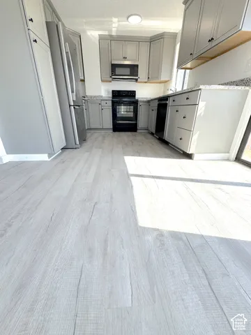Kitchen featuring shaker-style cabinetry, stone-finish countertops, stainless steel appliances, and wood-finish flooring