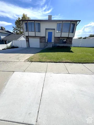 Split-level exterior featuring horizontal siding, stone veneer accents, multi-pane bay windows, and an attached single-car garage