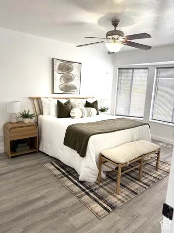 Wood-finish flooring, ceiling fan with integrated lighting, and multi-pane windows with horizontal blinds