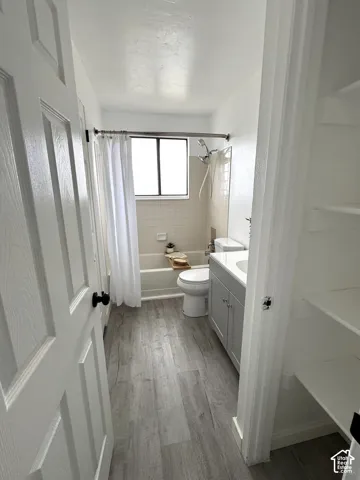 Bathroom featuring wood-finish flooring, a vanity with a solid-surface countertop, a tub-shower combination with tiled surround, and built-in shelving