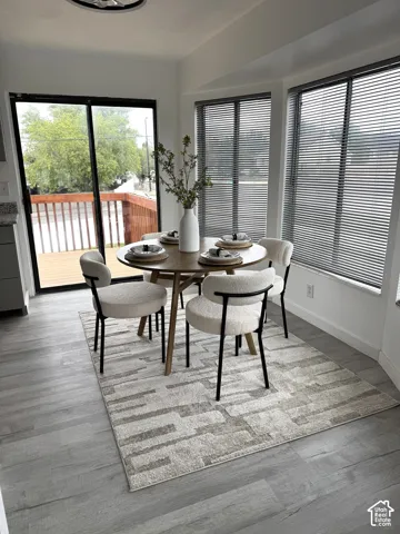 Wood-finish flooring, sliding glass door, bay windows with horizontal blinds, and neutral wall tones