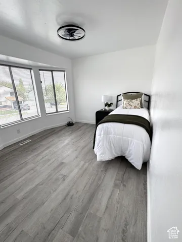 Room featuring neutral walls, wood-finish flooring, a bay window with multiple panes, and a flush-mount ceiling light fixture