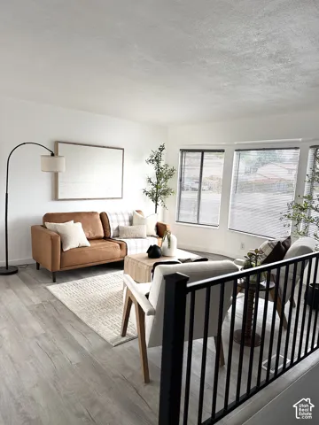 Living area featuring wood-finish flooring, large multi-pane windows, and a matte black metal railing