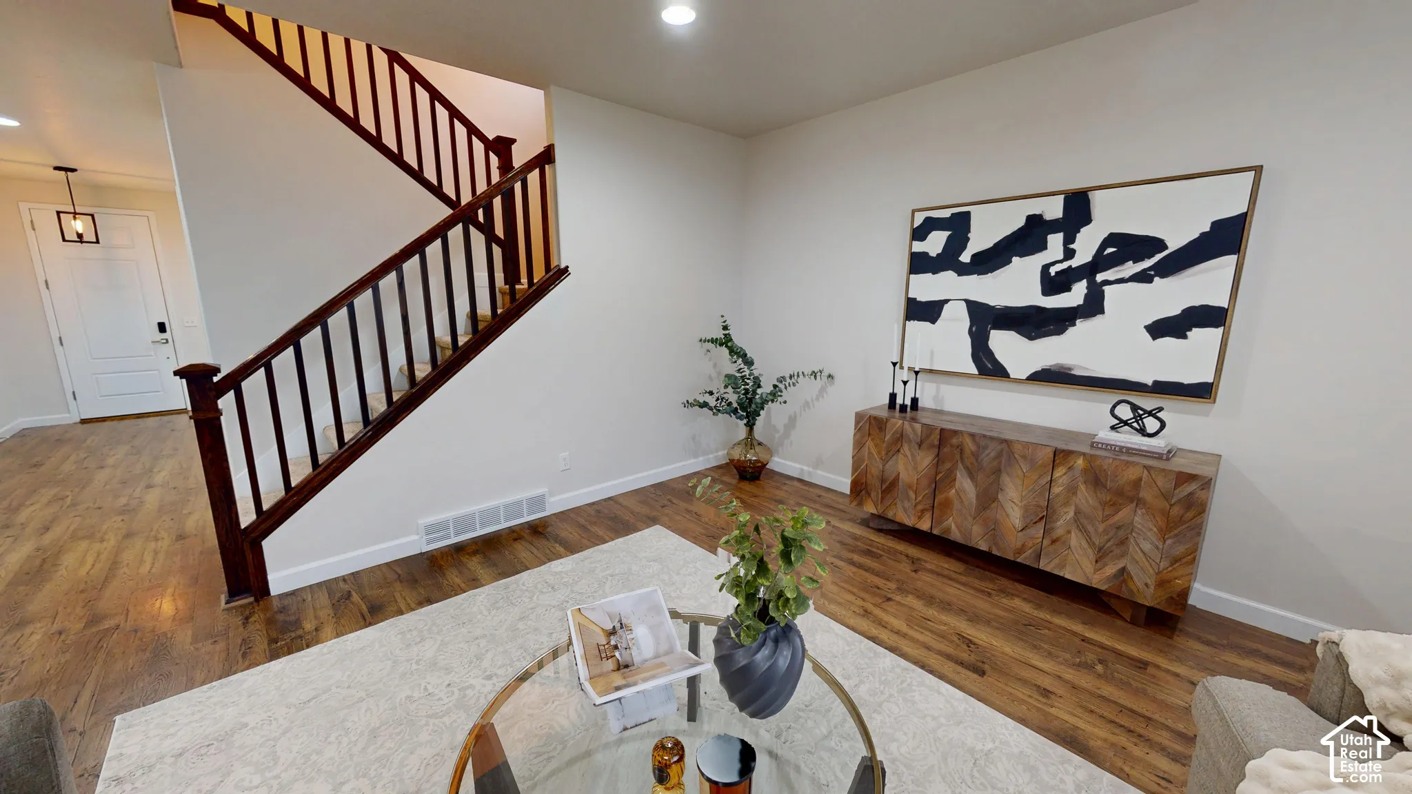 Open-concept space featuring wood-finish flooring, recessed lighting, and a staircase with a dark-stained wood railing and balusters