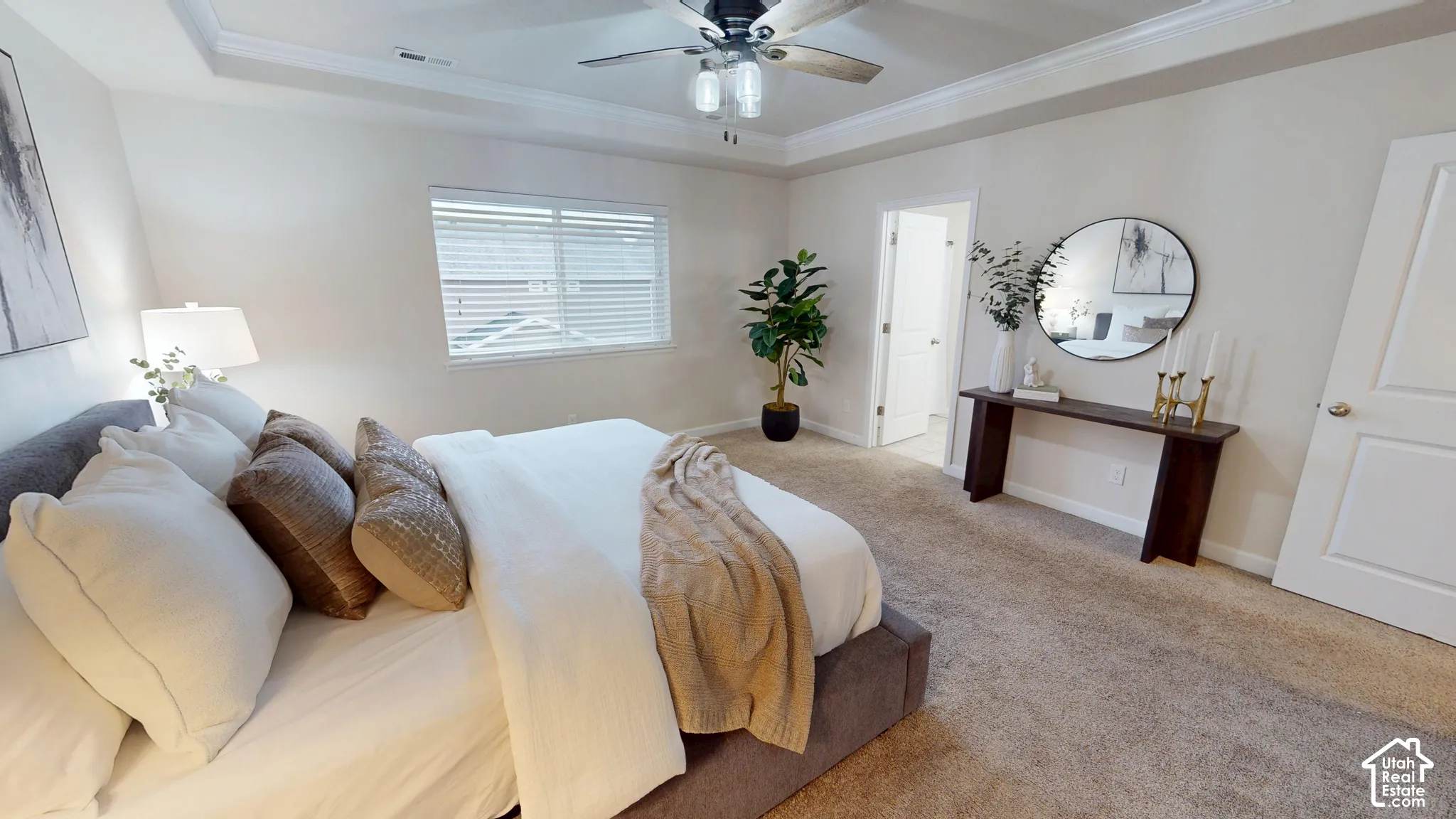 Bedroom featuring neutral carpeting, tray ceiling with recessed molding, and a multi-blade ceiling fan with integrated lighting