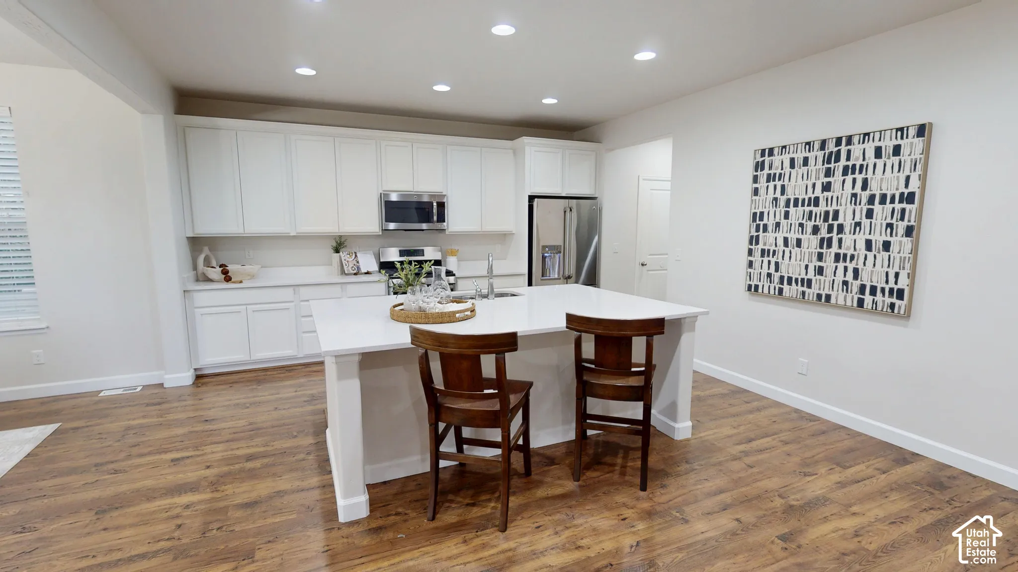 Kitchen featuring white cabinetry, center island with stone-finish countertop, stainless steel appliances, recessed lighting, and wood-finish flooring
