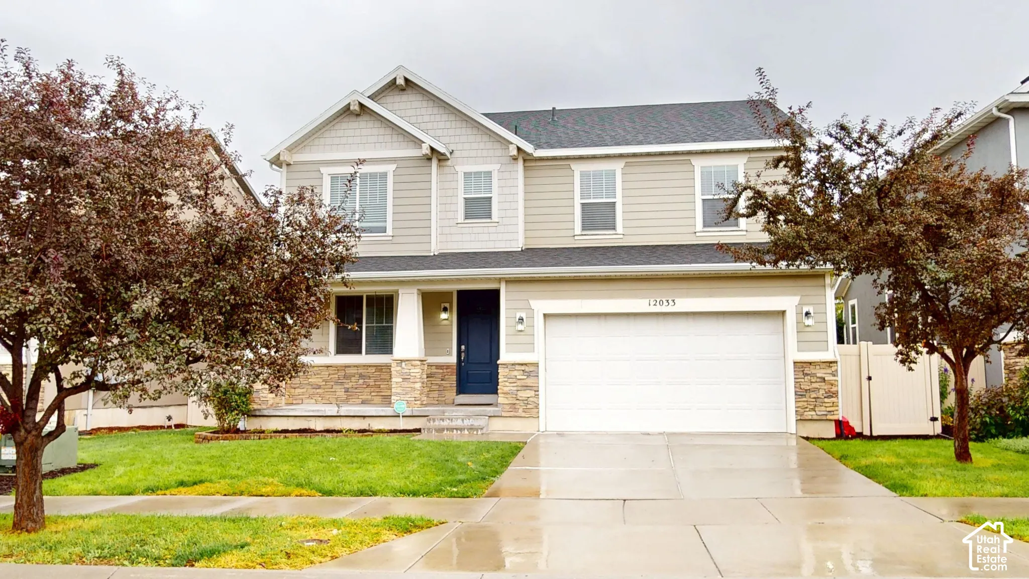 Two-story exterior featuring stone veneer accents, horizontal siding, shake-style siding in the gables, an attached two-car garage, and a covered entryway