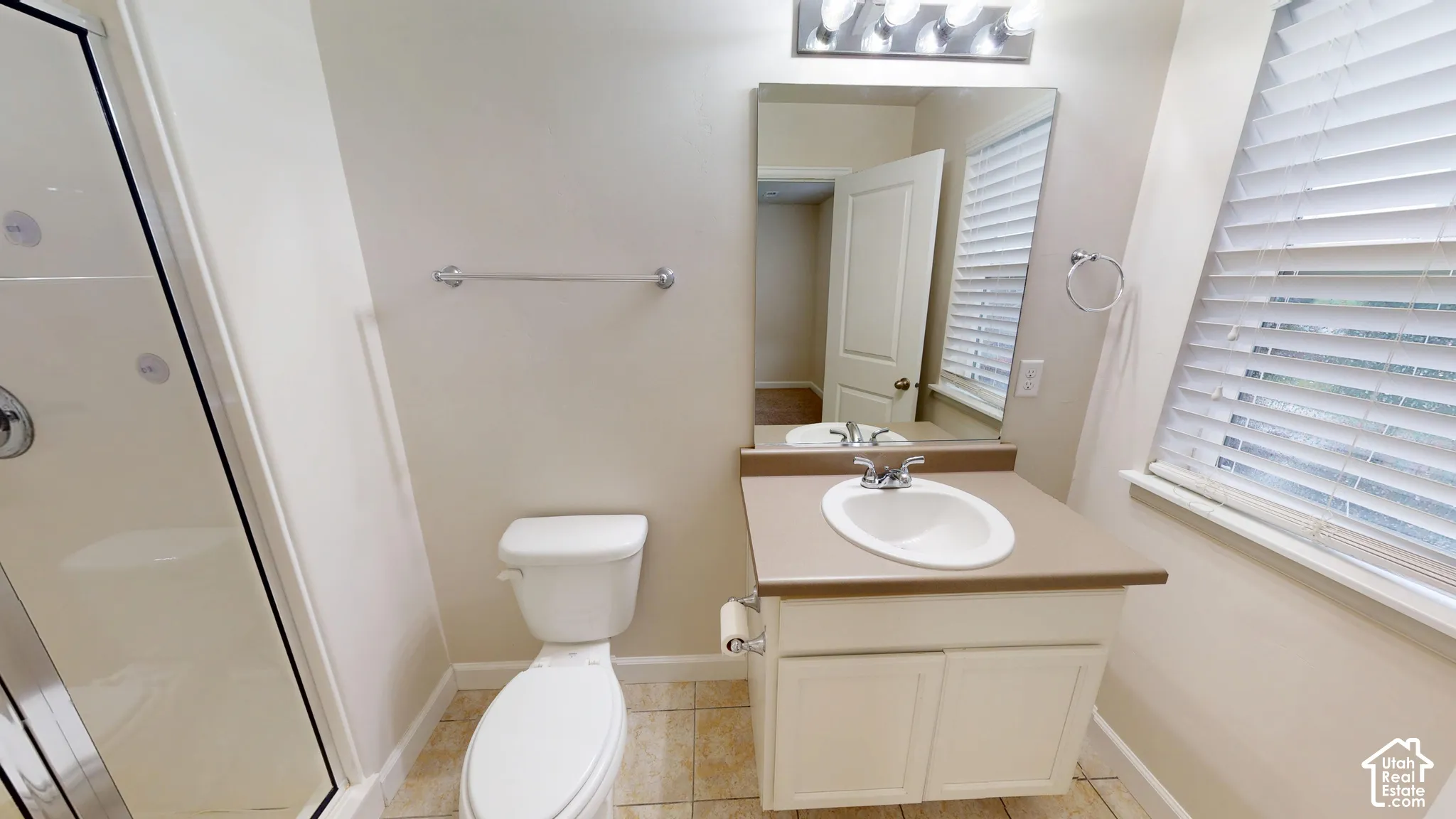 Upstairs ensuite 3/4 bathroom featuring a vanity with a solid-surface countertop and integrated sink, a glass-enclosed shower, tile flooring, and a large mirror with integrated lighting